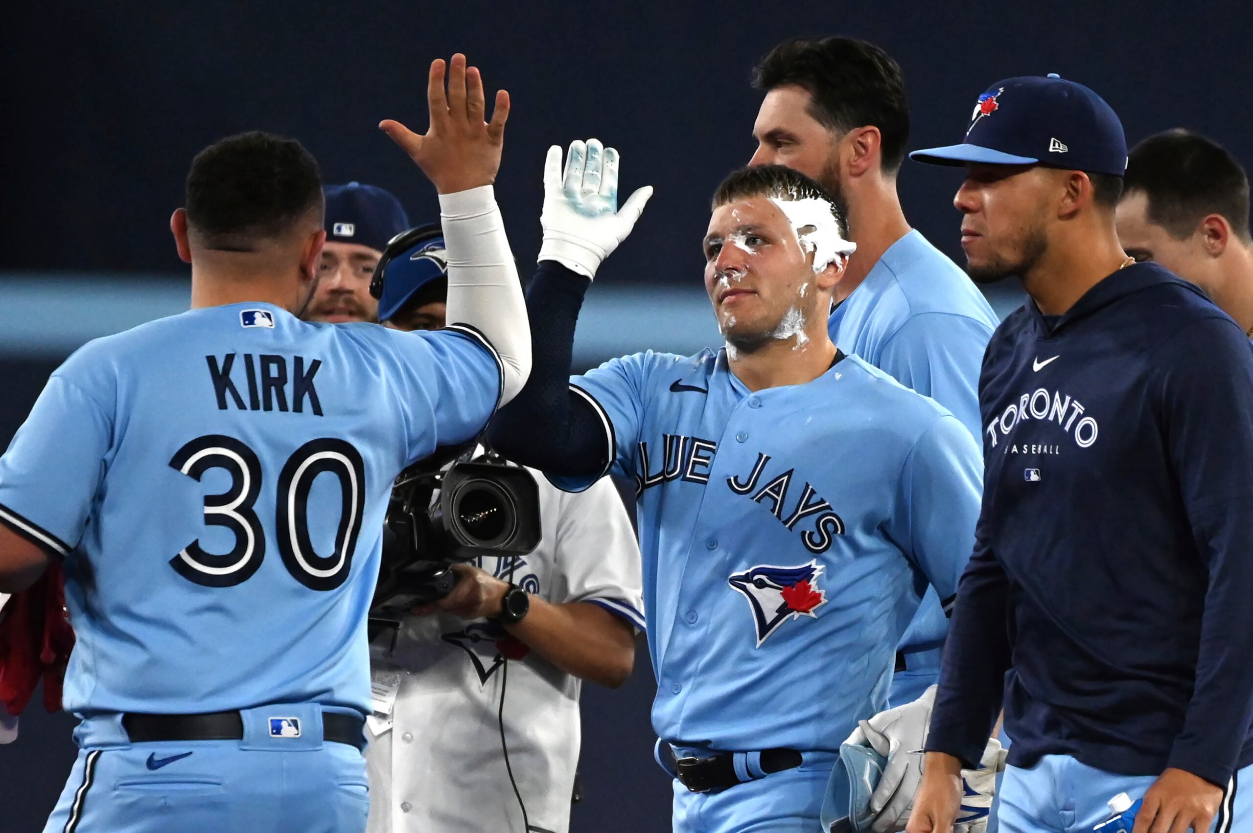 Daulton Varsho, de los Azulejos de Toronto, es felicitado tras ser embarrado de pastel durante el festejo por la victoria de su equipo ante los Marineros de Seattle.