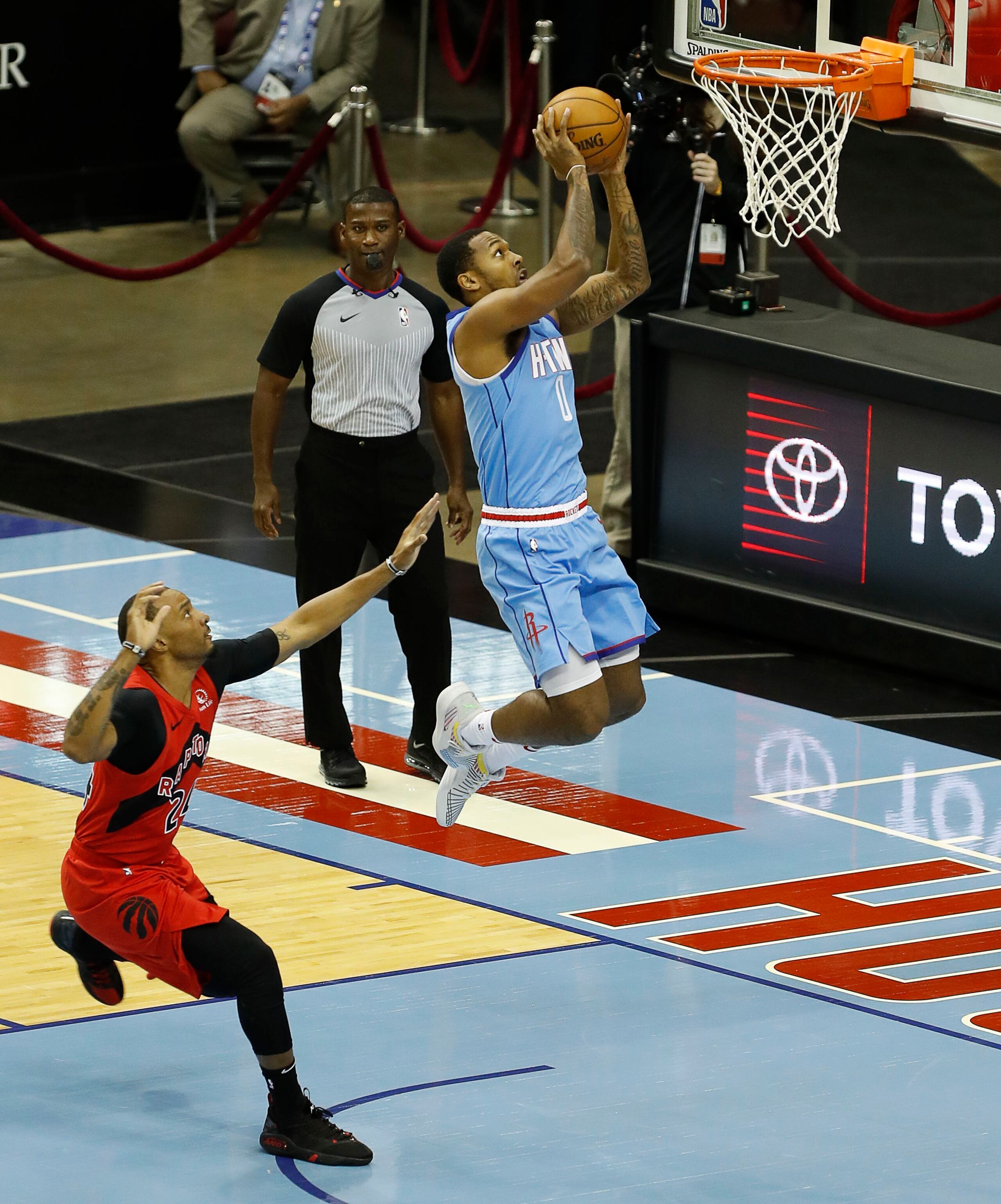 John Wall, de los Rockets de Houston, se apresta a colar un canasto tras dejar atrás a Norman Powell, de los Raptors de Toronto.