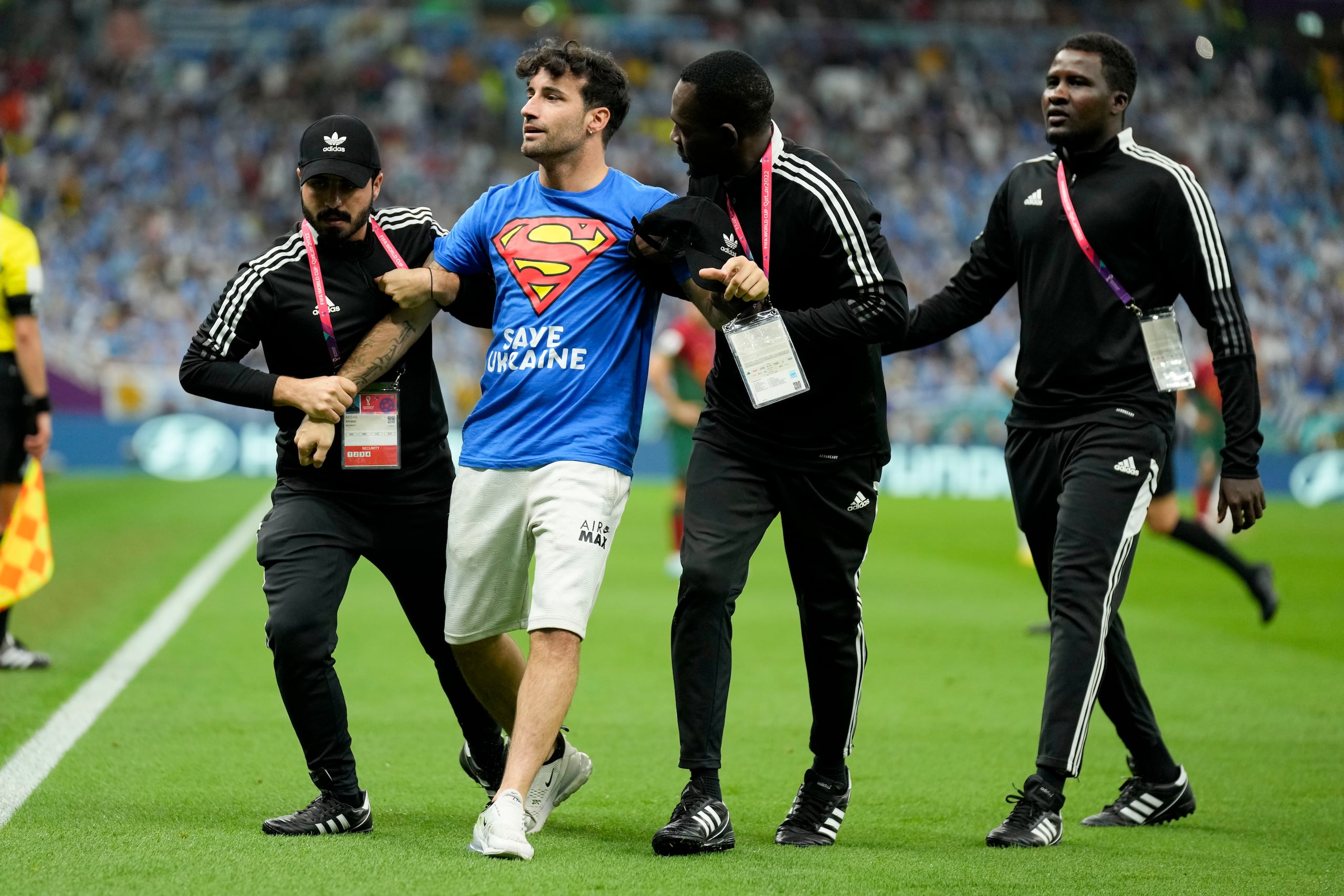 Un aficionado es detenido tras irrumpir en la cancha con la bandera arcoíris durante el partido del Grupo H entre Portugal y Uruguay, el lunes 28 de noviembre de 2022, en Lusail, Qatar. (AP Foto/Aijaz Rahi)