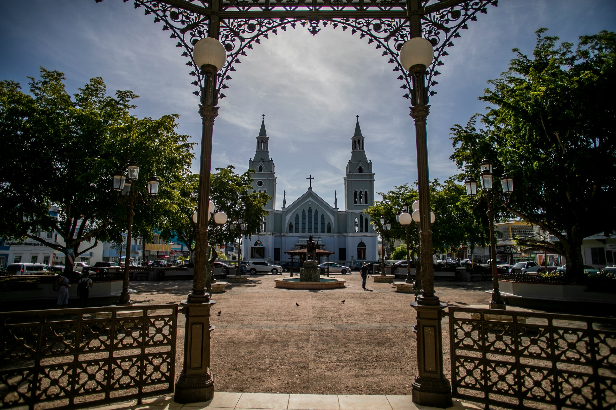 Al fondo de la plaza pública -hoy conocida como la Plaza Almirante Cristóbal Colón- se observa la parroquia San Francisco de Asís, que posee las dos torres más altas entre las antiguas iglesias católicas de Puerto Rico.