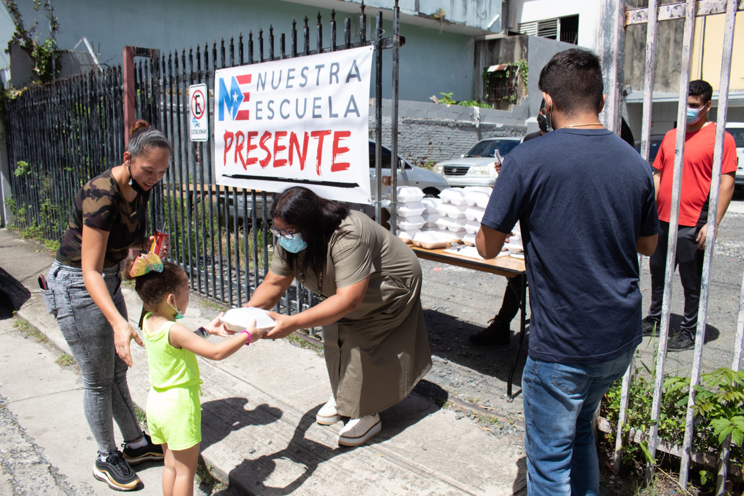 La iniciativa de almuerzos de Nuestra Escuela se une a otros esfuerzos que coordinan entidades como Urbe a Pie y el Centro de Apoyo Mutuo, que ofrecen alimentos calientes de míercoles a viernes. En la foto: Ana Yris Guzmán, presidenta ejecutiva de Nuestra Escuela, entrega un almuerzo a una niña.