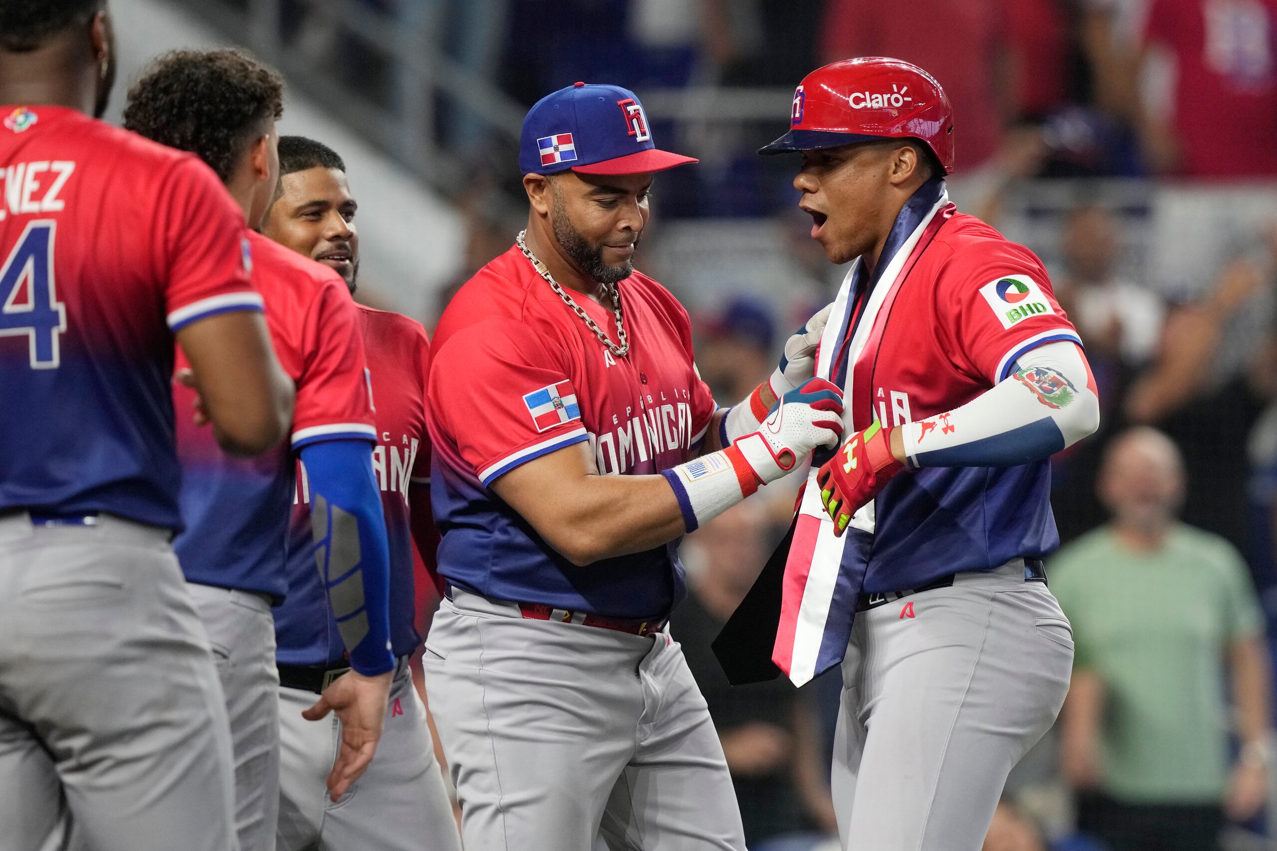 El jugador y gerente general del combinado de República Dominicana, Nelson Cruz, al centro, le entrega una banda presidencial al jardinero Juan Soto, a la derecha, luego de que este pegara un cuadrangular.