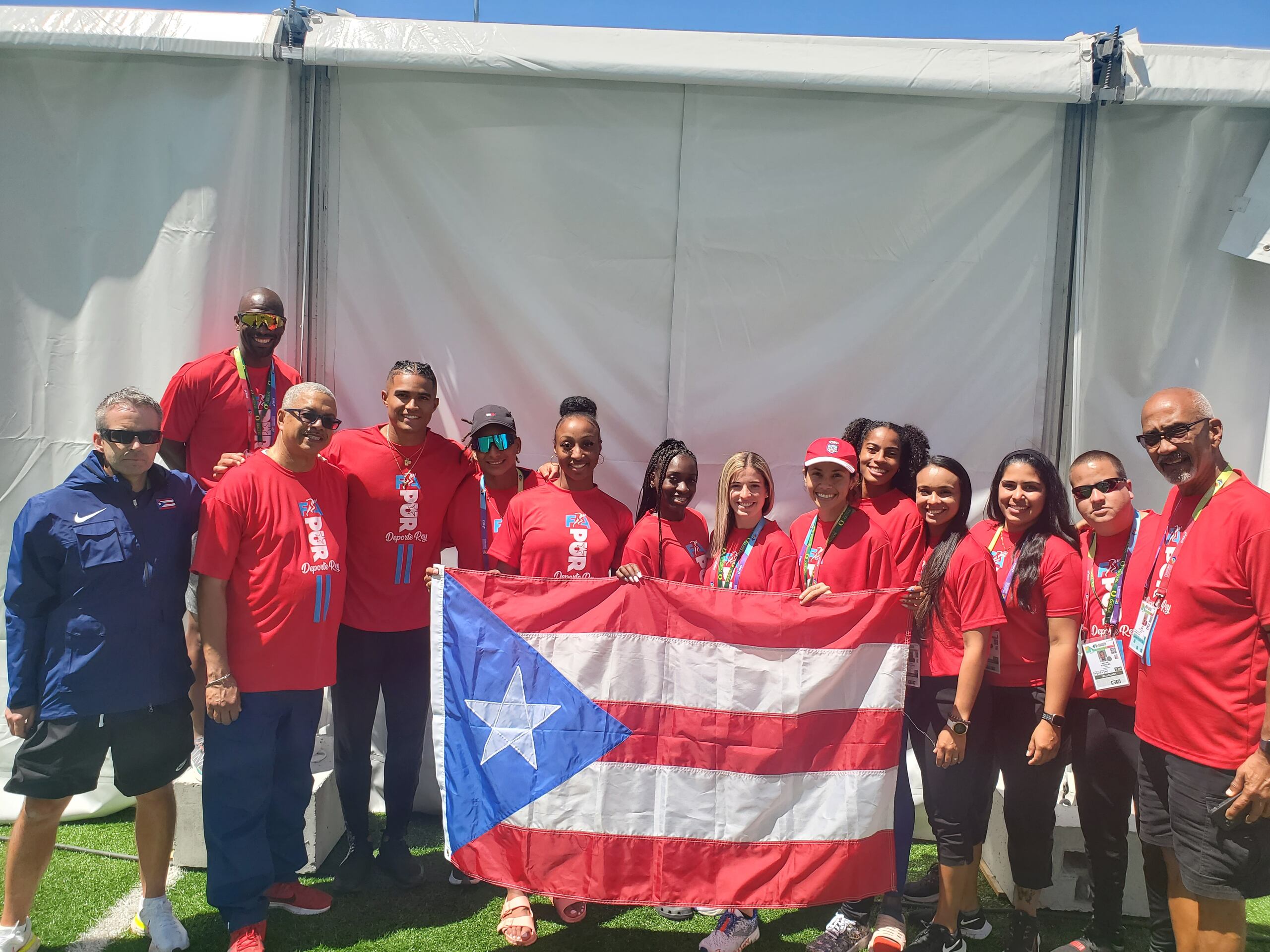 La delegación de Puerto Rico, incluyendo a la campeona olímpica Jasmine Camacho Quinn, posa con la bandera boricua.