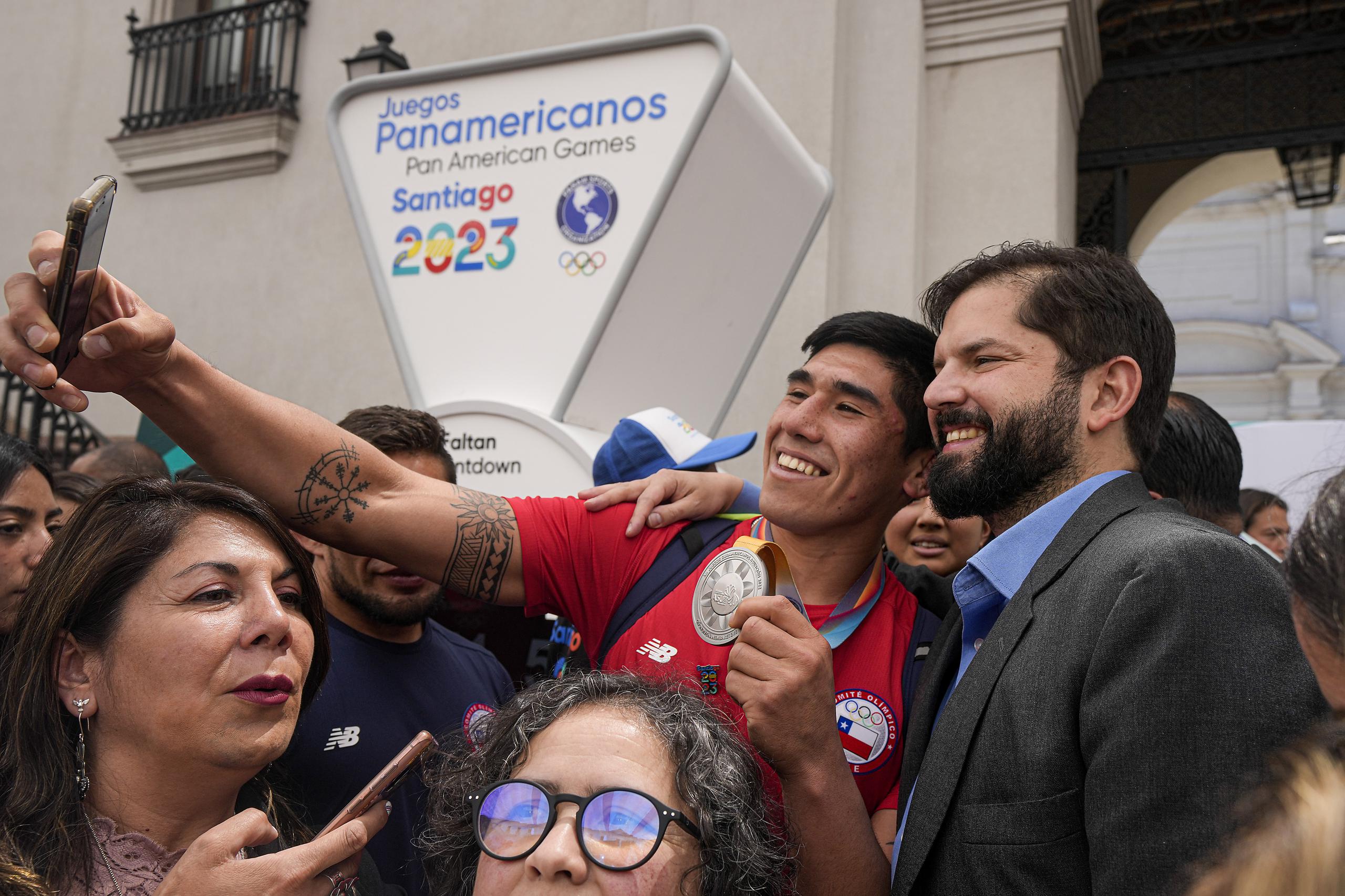 El presidente chileno Gabriel Boric posa para una selfie con un deportista chileno durante la ceremonia que marcó el inicio de la cuenta regresiva para los Juegos Panamericanos y Parapanamericanos de 2023 en el palacio presidencial en Santiago de Chile, hace casi un año atrás.