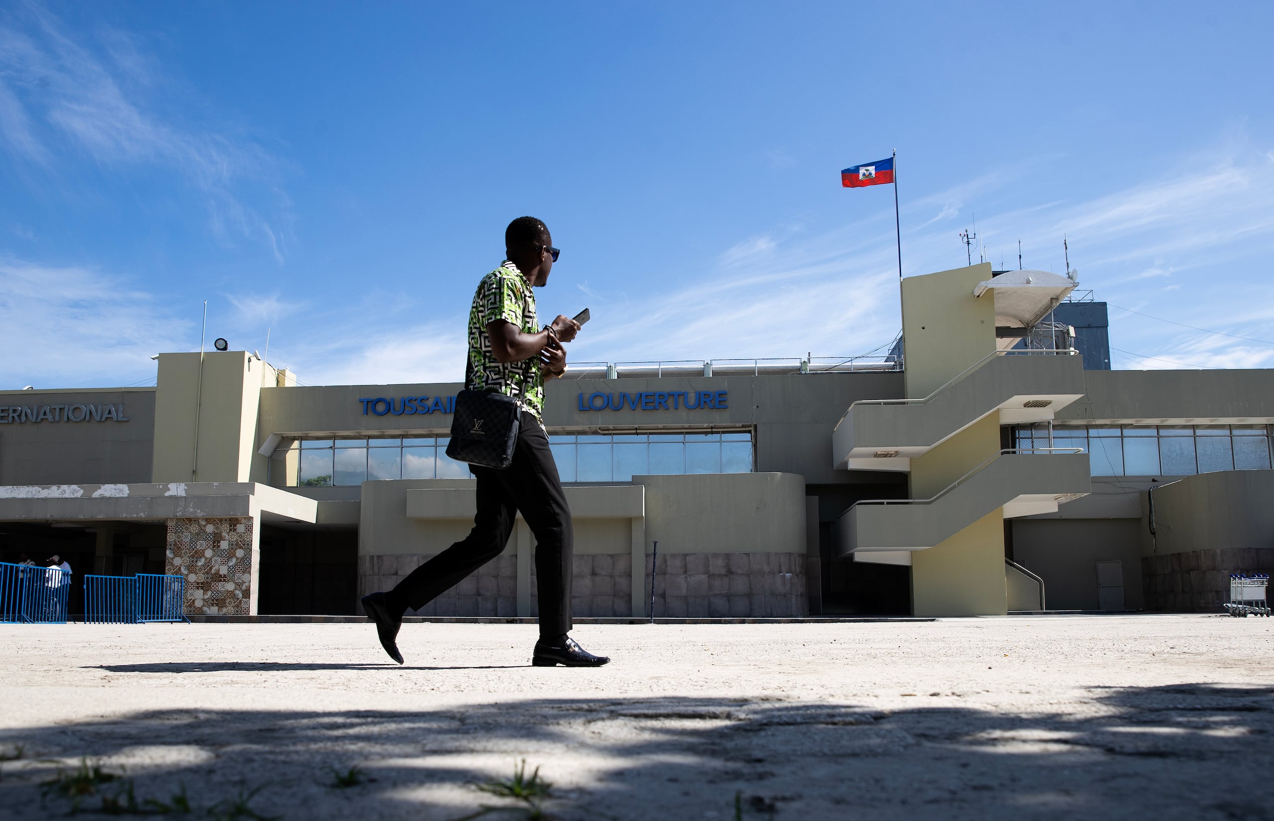 Un hombre camina frente a la entrada al aeropuerto internacional Toussaint Louverture este jueves en Puerto Príncipe (Haití). Los aviones volvieron a las pistas del aeropuerto internacional Toussaint Louverture este jueves tras tres meses de interrupción de operaciones debido a la situación de violencia en el país. EFE/ Orlando Barría
