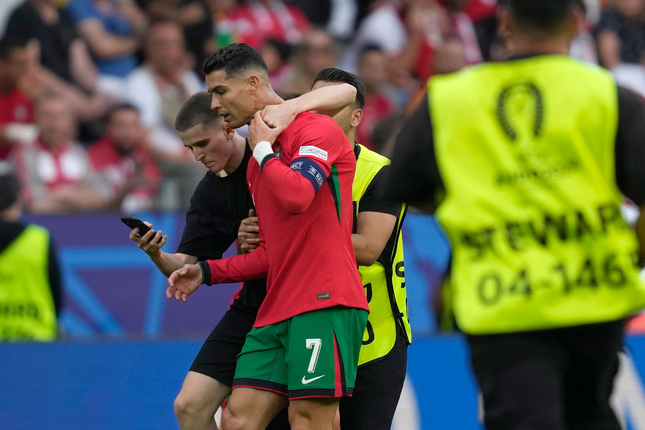 Un invasor de campo intenta tomarse una selfie con Cristiano Ronaldo mientras un guardia lo saca durante un partido del Grupo F de la Eurocopa entre Turquía y Portugal.