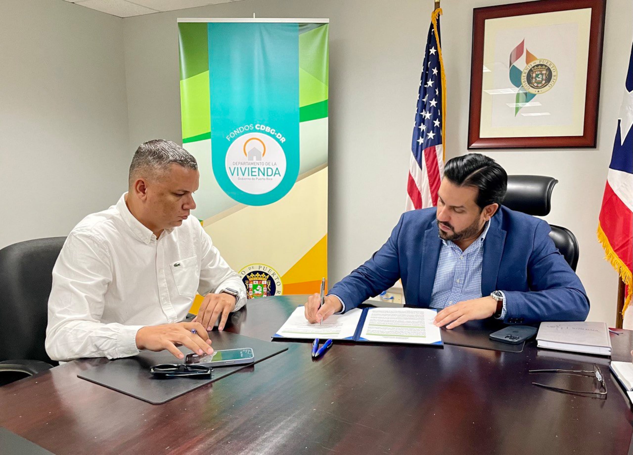 El alcalde de Guánica, Ismael Rodríguez Ramos junto al secretario de la Vivienda, William Rodríguez, durante la firma del acuerdo.