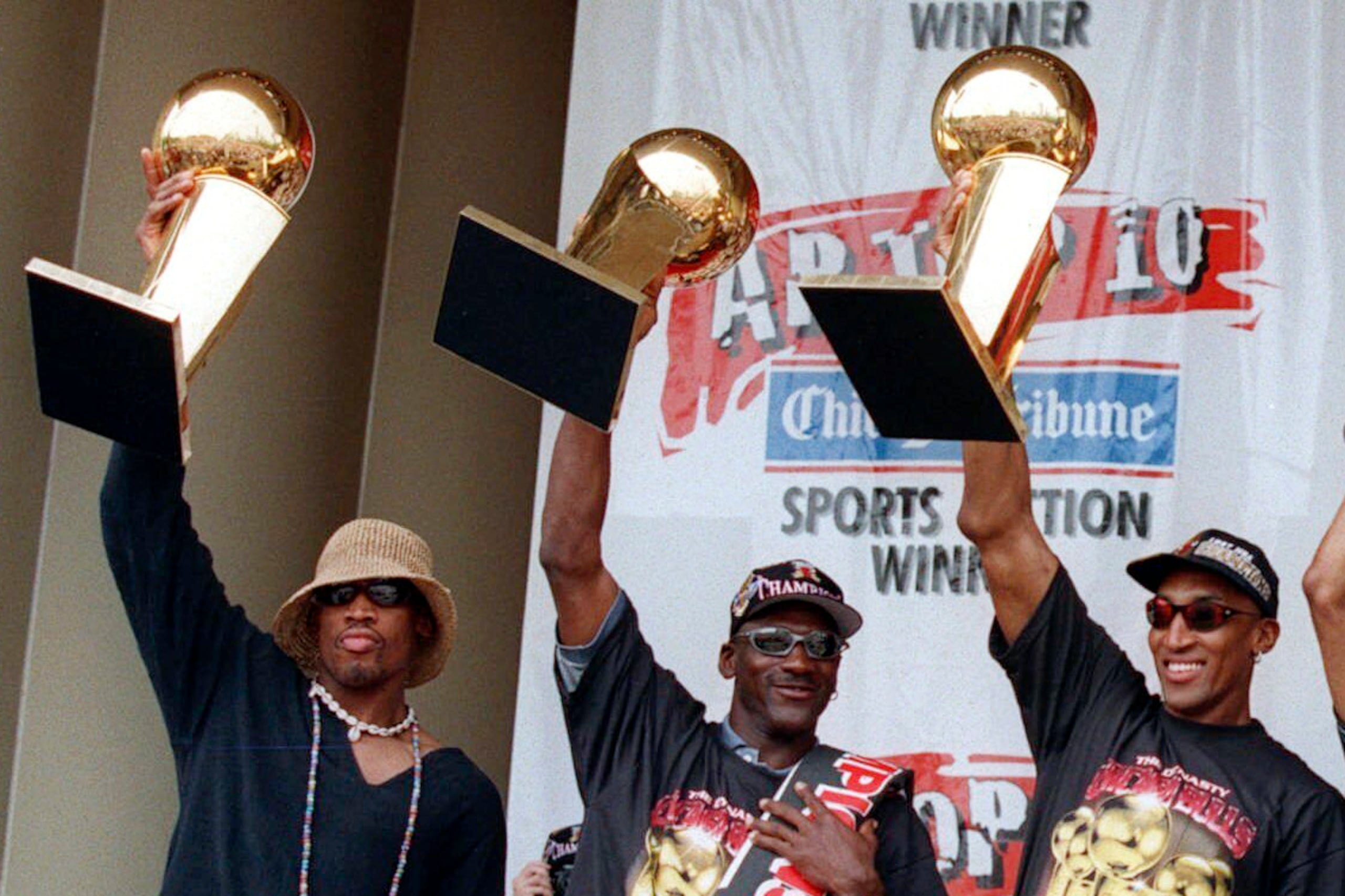De izquierda a derecha, Dennis Rodman, Michael Jordan y Scottie Pippen, exjugadores de los Bulls de Chicago, sostienen tres de los trofeos del equipo, durante una ceremonia realizada el 16 de junio de 1997.
