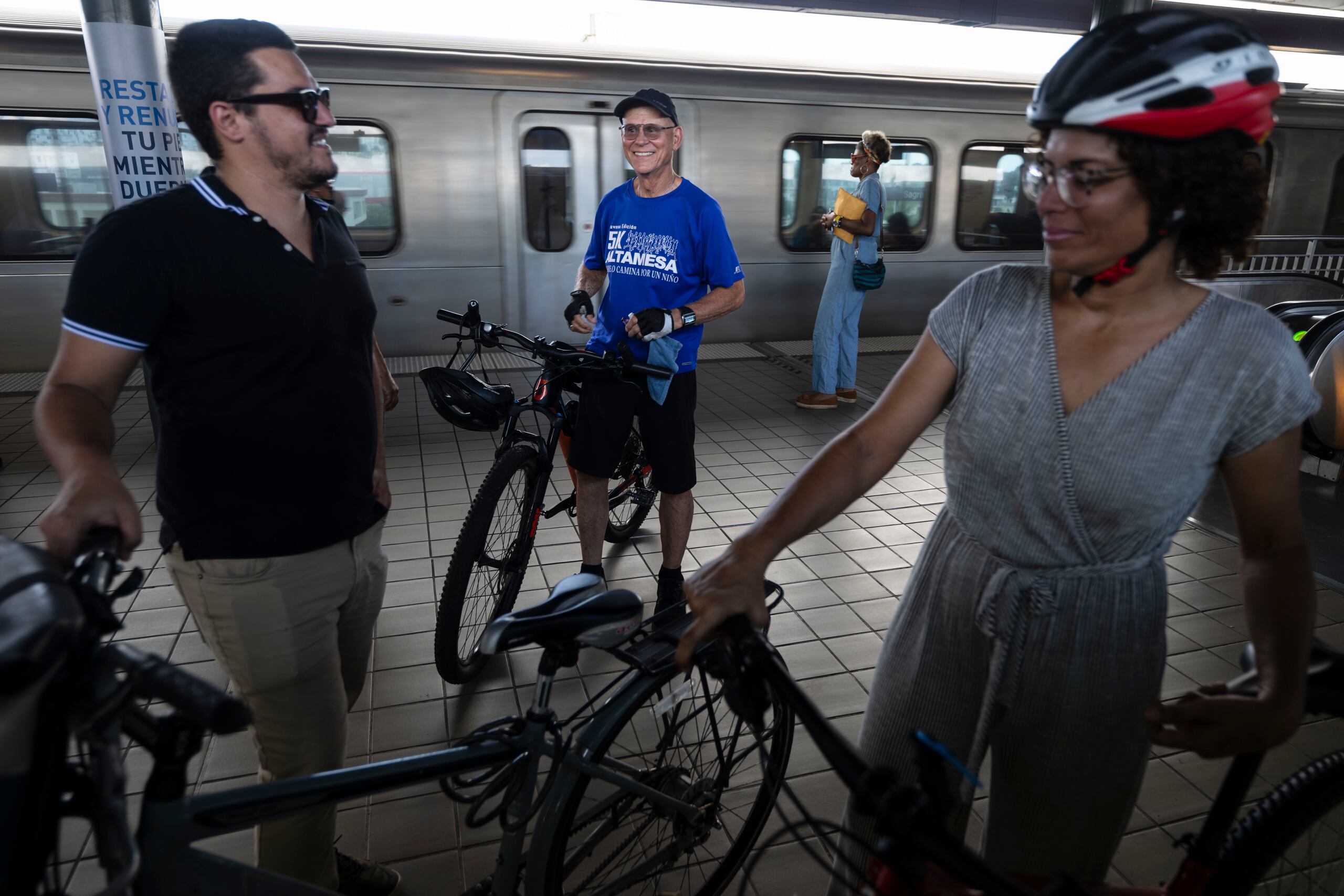 David Soto, consultor de ATI, junto a Ylenia González, promotora de Muévete en Bici Puerto Rico, conversan con otro ciclista en una de las plataformas de abordaje del Tren Urbano.
